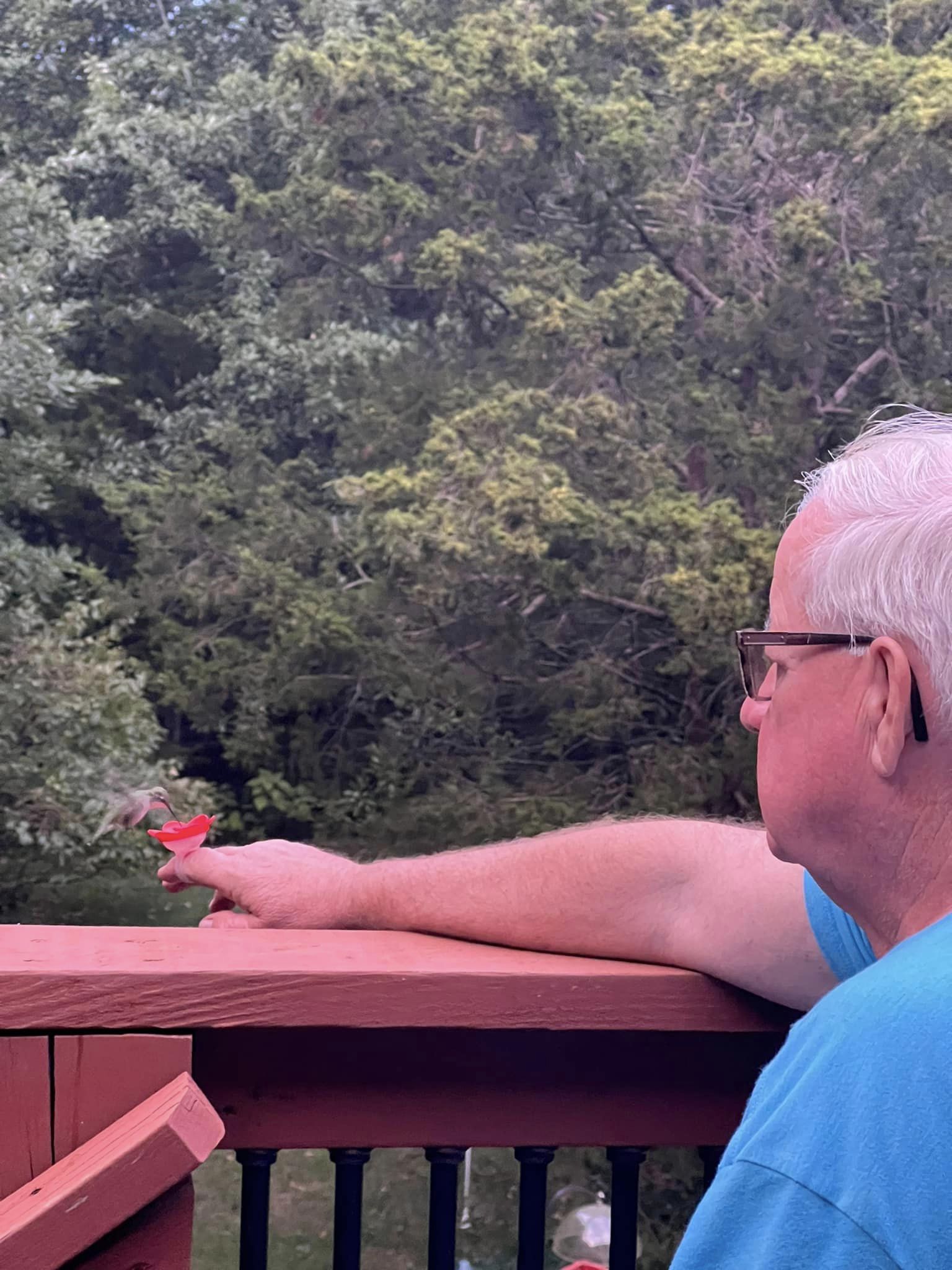 Bird Man Mel feeding a Hummingbird from a Hummer Ring